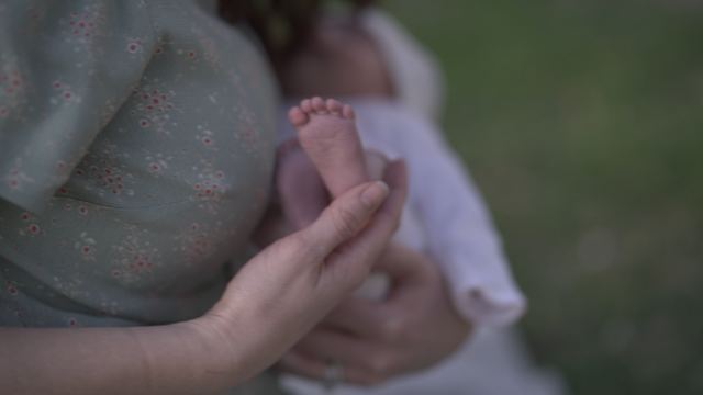 A mother's hand cradling a newborn's foot.