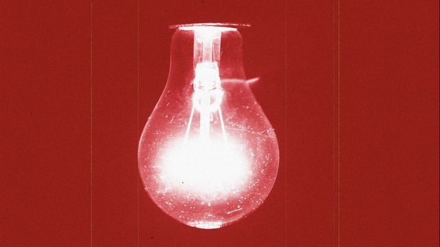 A bare lightbulb glowing against a deep red background.