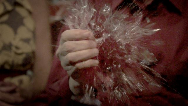 A hand crushing a glass as it shatters.