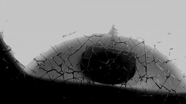 An eye seen through shattered glass.