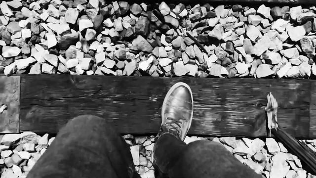 Looking down at a boot stepping onto a railroad tie.